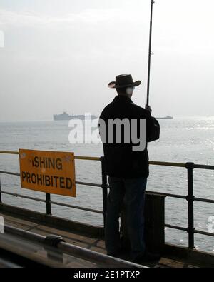 Mann Angeln gegen Angeln verboten Schild am Pier, Essex Stockfoto