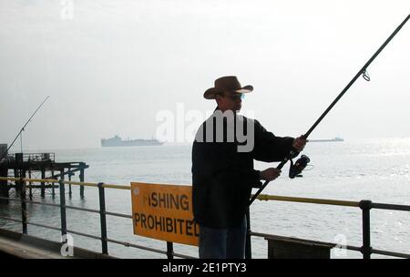 Mann Angeln gegen Angeln verboten Schild am Pier, Essex Stockfoto