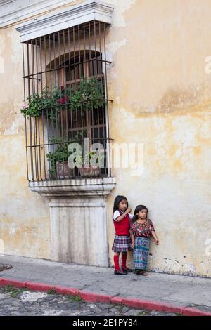 Ein Schulmädchen und ihre jüngere Schwester in traditioneller Maya-Kleidung Auf der Straße in Antigua Guatemala Stockfoto