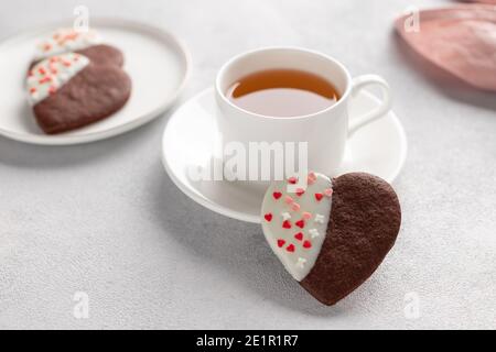 Nahaufnahme von herzförmigen Schokoladenkeksen und einer Tasse Tee Stockfoto