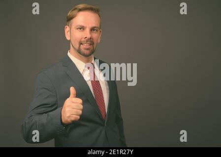 Blond bärtigen Geschäftsmann mit Spitzbart gegen grauer Hintergrund Stockfoto