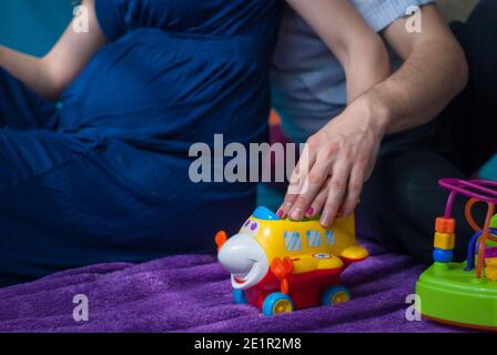 Schwangere Frau in einem blauen Kleid sitzt mit ihrem Mann Stockfoto
