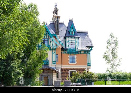 Fast fertig Fachwerkhaus mit Stein-Basis und Stein-fertigen Boden Boden mit renovierten Eingangstüren und großen Baum vor Einer Hecke Stockfoto