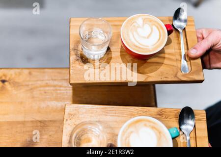 Zwei Tassen Cappuccino auf Holztabletts. Kaffee- und Kellnerkonzept Stockfoto