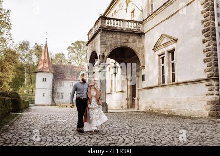 Wunderschöne Hochzeit Paar umarmt und zu Fuß in der Nähe des alten Schlosses in sonnigen schönen Park. Stilvolle schöne Braut und Bräutigam posiert auf dem Hintergrund der alten Stockfoto