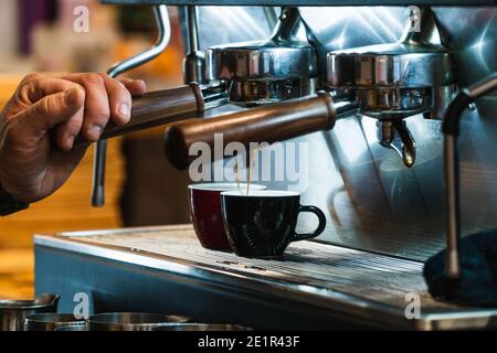 Nahaufnahme eines Barista, der Kaffee in einem professionellen Kaffee zubereitet Maschine Stockfoto