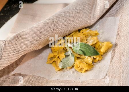 Ravioli del Plin typisch piemontesische gefüllte Pasta aus der Langhe gewürzt mit Butter und Salbei und Parmesan, traditionell auf Serviette serviert Stockfoto