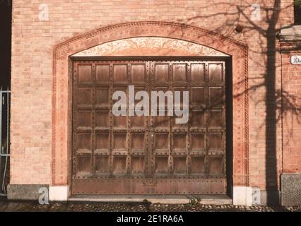 Garage in einem alten Backsteinhaus mit großen besetzt hölzernen Zugangstür und dekorierten Rahmen.Externes architektonisches Objekt der Gebäudestruktur. Stockfoto