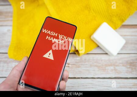 Waschen Sie Ihre Hände Zeichen auf rotem Hintergrund auf dem Smartphone angezeigt Schirm mit Seife und Handtuch Stockfoto