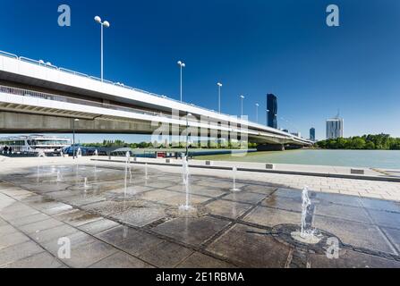 Brunnen vor der Reichsbrücke über die Donau mit der Donau City im Hintergrund in Wien, Österreich. Stockfoto