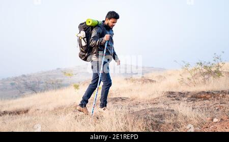 Seitenansicht bewegte Weitwinkelaufnahme des Reisenden mit Rucksack Wandern auf dem Berg durch Halten Stock im Winter - Konzept Von solo wandern oder Trekking Stockfoto