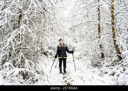 Junge Frau im verscheiten Wald im Sauerland, Sundern, Hochsauerlandkreis, Nordrhein-Westfalen bei einem Spaziergang in einem verschneiten Wald in Sundern, Stockfoto