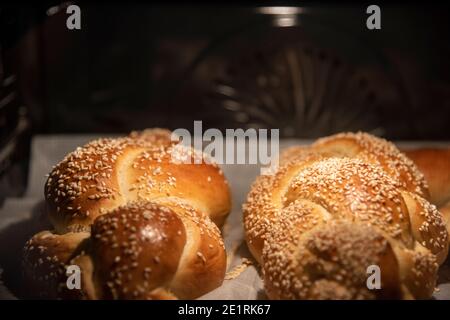 Hausgemachtes Challah-Brot backen. Zopf-Challah mit Sesamsamen auf einem Backblech im Ofen. Hochwertige Fotos Stockfoto