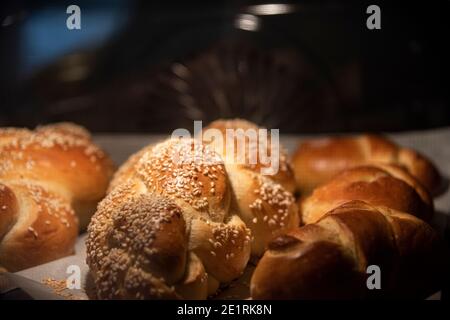 Hausgemachtes Challah-Brot backen. Zopf-Challah mit Sesamsamen auf einem Backblech im Ofen. Hochwertige Fotos Stockfoto