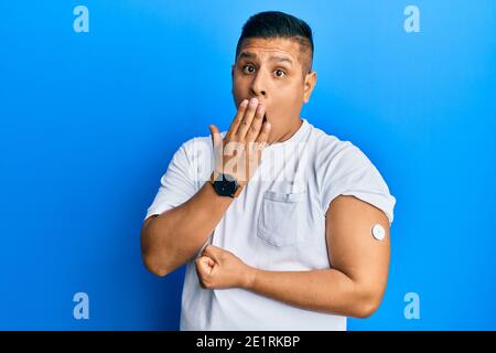 Junger lateinischer Mann mit Blutzucker-Meter-Taste deckt den Mund mit der Hand, schockiert und Angst vor Fehler. Überrascht Ausdruck Stockfoto
