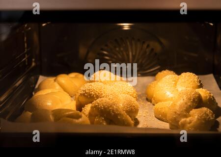 Hausgemachtes Challah-Brot backen. Zopf-Challah mit Sesamsamen auf einem Backblech im Ofen. Hochwertige Fotos Stockfoto