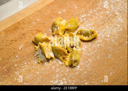 Ravioli del plin, typische Pasta aus Langhe, Piemont, Italien - frisch zubereitete rohe Agnolotti auf Holzschneidebrett Stockfoto