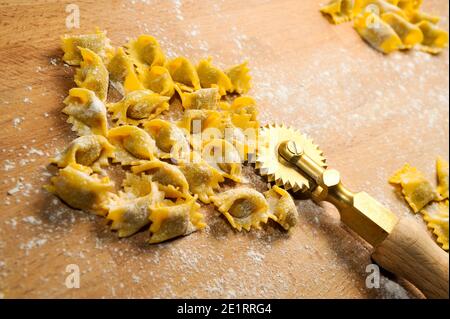 Ravioli del plin, typische Pasta aus Langhe, Piemont, Italien - agnolotti mit Radmesser auf Holzschneidebrett Stockfoto