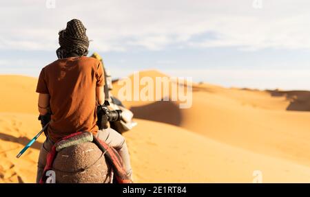(Selektiver Fokus) atemberaubende Aussicht auf zwei Menschen, die Kamele auf den Sanddünen in Merzouga, Marokko reiten. Stockfoto
