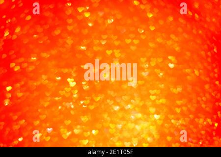 Unscharfer Bokeh-Hintergrund. Textur aus rot orangenen Herzen. Vorbereitung auf eine Weihnachtskarte. Abstrakter Valentinstag, festliche Liebe Stockfoto