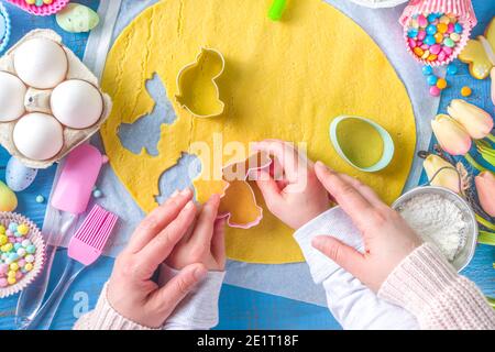 Familie hausgemachten Urlaub Ostergebäck Konzept. Osterbacken Hintergrund mit Mutter und Tochter Kind Hände, flachlegen Draufsicht. Mit Teig bildet sich ein Cupcake Stockfoto