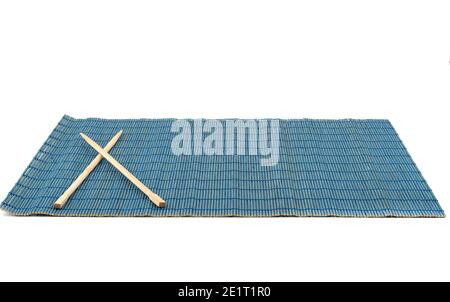 Blaue Bambus-Futtermatte mit Essstäbchen isoliert auf weißem Hintergrund. Traditionelle Küchenutensilien. Stockfoto
