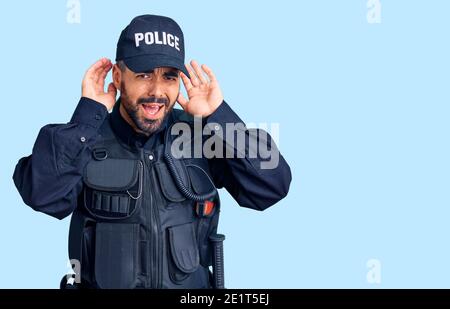 Junger hispanic Mann in Polizeiuniform versucht, beide Hände auf Ohr Geste hören, neugierig auf Klatsch. Hörproblem, taub Stockfoto
