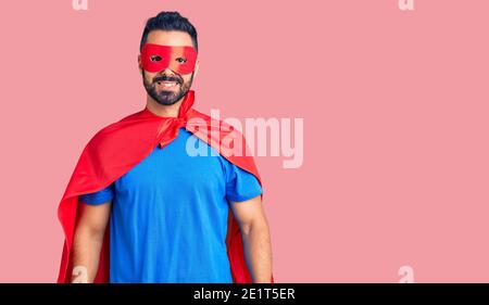 Junge hispanic Mann trägt super Helden Kostüm sieht positiv und Glücklich stehen und lächeln mit einem selbstbewussten Lächeln zeigt Zähne Stockfoto