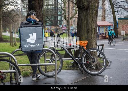 Deliveroo Radler bei einer Pause auf dem Middle Meadow Walk, Edinburgh, Schottland, Großbritannien. Stockfoto