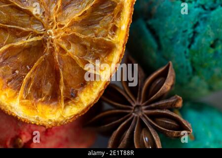 Gewürze und kandierte Früchte aus nächster Nähe. Sternanis und getrocknete Orange auf dem Hintergrund von bunten Keksen. Das Konzept des Winterfood Stockfoto