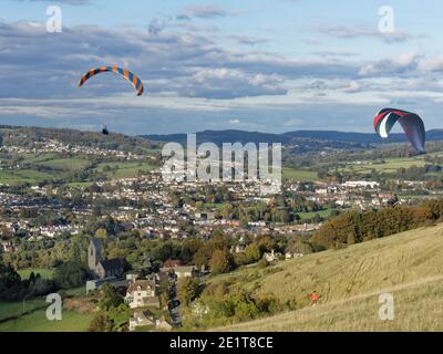 Gleitschirme fliegen von Selsley Hill, mit Selsley Village und Stroud im Hintergrund, Gloucestershire, UK, Oktober. Stockfoto