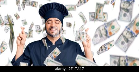Junge hispanic Mann trägt Herd Uniform gestikulierenden Finger überquert lächelnd mit Hoffnung und Augen geschlossen. Glück und abergläubischen Konzept. Stockfoto