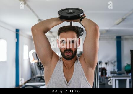 Mann macht Trizeps mit Hanteln auf dem Rücken. Stockfoto