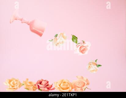 Kreatives Frühlingskonzept mit Natur Rosen Blumen Dekoration und rosa Glas auf rosa Pastell minimal Hintergrund Flat Lay, Draufsicht Stockfoto