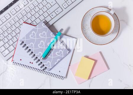 Flacher Business-Schreibtisch mit Kommunikationsgerät, Tee- und Schreibgeräten. Feminine Business Mockup, Copyspace, weißer Hintergrund. Stockfoto
