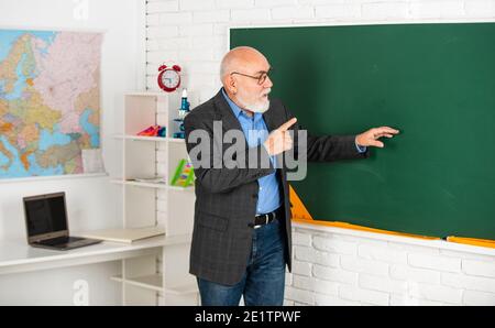 Oberlehrer erklären Thema an der Tafel. Lehrer für Geographie. Klassenzimmer mit Karte. Zurück zur Schule. Bildung in der modernen Schule. Bärtiger Mann zeigen etwas. Raum kopieren. Stockfoto