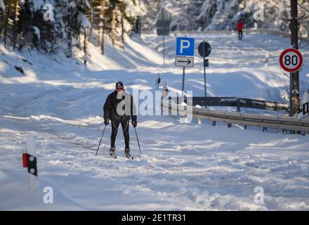 Schmitten, Deutschland. Januar 2021. Ein Mann ist auf der deutschen Limes Road mit Langlaufskiern unterwegs. Die Straße zum Feldberg ist nicht geräumt und für den Autoverkehr gesperrt. Das Feldberg-Gebiet im Taunus ist wegen Schneebruchs geschlossen und um einen Ansturm von Winterausflüglern zu vermeiden. Der Gipfel ist nur ohne motorisierten Transport erreichbar. Quelle: Andreas Arnold/dpa/Alamy Live News Stockfoto