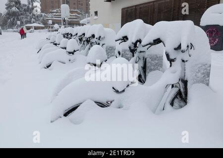 Madrid, Spanien - 09. Januar 2021: Reihe von elektrischen Fahrrädern des öffentlichen Dienstes der EMT-Firma, Bicimad, im Schnee begraben, an einem verschneiten Tag, wegen t Stockfoto