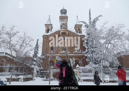 Madrid, Spanien - 09. Januar 2021: Ein junger Mann auf Skiern fährt an einem verschneiten Tag vor der Iglesia del Hospital Niño Jesus, wegen der Filomena Pola Stockfoto