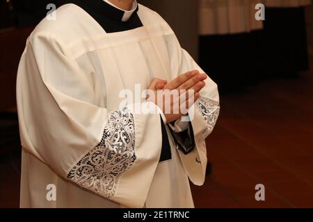 Junger Priester mit gefalteten Händen im Gebet Stockfoto