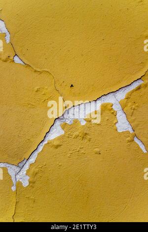 Alte gelbe Strukturwand mit Rissen in Weiß. Schöner Hintergrund. Die Farbe des Gebäudes war kaputt. Stockfoto