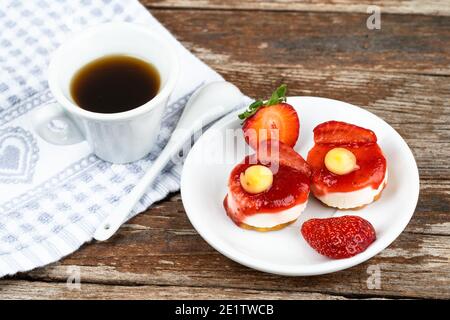 Weiße Tasse Espresso mit Erdbeeren und lila Blumen Auf einem Tisch bereit zum Frühstück italienische Gebäck Stockfoto