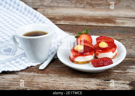 Weiße Tasse Espresso mit Erdbeeren und lila Blumen Auf einem Tisch bereit zum Frühstück italienische Gebäck Stockfoto