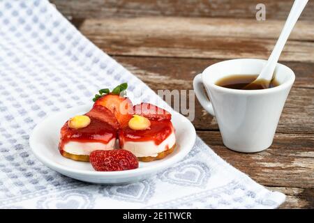 Weiße Tasse Espresso mit Erdbeeren und lila Blumen Auf einem Tisch bereit zum Frühstück italienische Gebäck Stockfoto