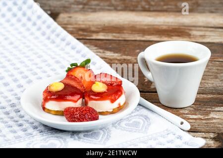 Weiße Tasse Espresso mit Erdbeeren und lila Blumen Auf einem Tisch bereit zum Frühstück italienische Gebäck Stockfoto