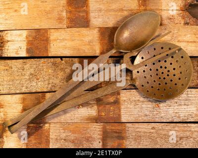 Altes Besteck auf einem Holztisch mit Löffeln und Gabeln.Löffel, Gabeln, Messer, Schöpflöffel auf einem Holztisch, selektiver Fokus und getöntes Bild Stockfoto