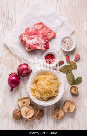 Zutaten für herzhafte Sauerkrautsuppe (Sauerkrautsuppe) mit Fleisch, Oonioc, Knoblauch und Gewürzen auf Holztisch Stockfoto