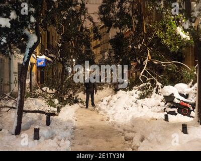 Madrid, Spanien. Januar 2021. Ein Mann, der in der Nacht in einer Straße mit Ästen von umgestürzten Bäumen aufgrund des Schneefalls des Sturms Filomena bedeckt. Sturm Filomena trifft Madrid (Spanien), ein Wetteralarm wurde für kalte Temperaturen und schwere Schneestürme in ganz Spanien ausgegeben; nach Angaben der Wetteragentur Aemet wird voraussichtlich einer der schneesichersten Tage der letzten Jahre sein. © Valentin Sama-Rojo/Alamy Live News. Stockfoto