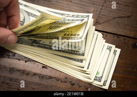 Handzählstapel von hundert US-Banknoten auf Holztisch Hintergrund. Bargeld von hundert Dollar-Scheine, Papiergeld Währung. Stockfoto