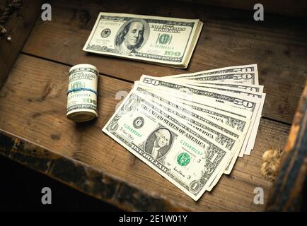 Menge der US-Banknoten auf Geldstapel und in Rolle in Holzschublade. Bargeld von hundert Dollar Scheine, Papier Währung Hintergrund. Stockfoto